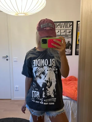Svart tvättad t-shirt med Blondie-tryck - Cool grå/svart tvättad t-shirt med stort vitt Blondie-tryck framtill och textdetaljer🩶🤍 Oversized passform och korta ärmar, snygg till jeans eller shorts. Materialet är bomull.