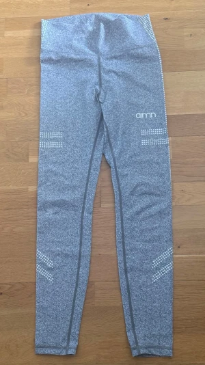 Gråmelerade AIM'N leggings - Snygga gråmelerade leggings från AIM'N med hög midja och vita prickdetaljer längs sidorna och benen. Stretchigt material som sitter skönt och följer kroppen. Perfekta för träning eller chill. AIM'N-logga på låret och coola mönster längs benen.
