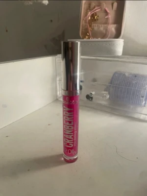 Essence Cranberry Lip Oil - Glansigt läppglans från Essence i färgen Cranberry. Kommer i en smidig tub med silverfärgat lock och transparent hylsa som visar den klarröda oljan. Ger en fräsch och saftig look till läpparna med en hint av bärig färg.