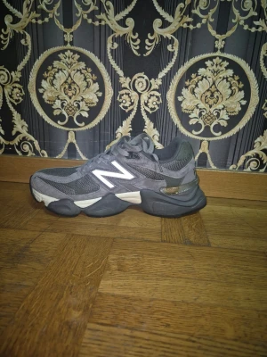 Grå New Balance sneakers - Säljer ett par grå New Balance sneakers med vit logga på sidan. Skorna har en chunky sula, snörning och är tillverkade i en mix av mocka och mesh för en sportig look. Perfekta för dig som gillar streetwear och bekväma skor. Helt nya köpte fel storlek 
