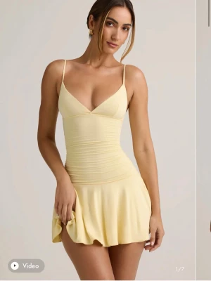 Ljusgul Oh Polly klänning  - Supersöt ljusgul kort klänning med smala axelband och v-ringning. Klänningen har figurnära passform upptill och en lätt utställd kjol som ger en lekfull look. Perfekt för varma dagar och sommarens alla tillfällen.