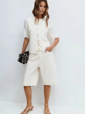 Offwhite stickad kortärmad kofta Gina Tricot - Säljer en offwhite stickad kofta med korta ärmar och knappar framtill. Koftan har en avslappnad passform och är tillverkad i ett mjukt, lätt material som ger en skön känsla. Perfekt att slänga över en topp för en enkel men snygg look.