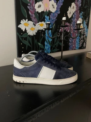 Valentino Flycrew  - Snygga sneakers från Valentino i blå mocka med vita detaljer och vit sula. Skorna har blå skosnören och en klassisk låg siluett. Perfekta för dig som vill ha en stilren och exklusiv look med premiumkänsla.