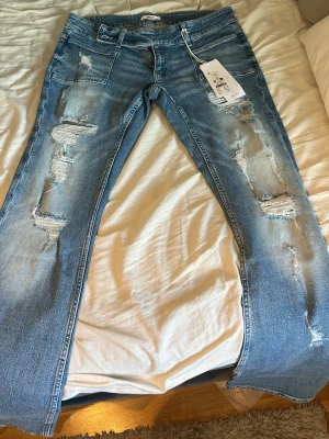 Ljusblå slitna flare jeans - Ljus blå jeans från Gina. Helt nya med prislappen kvar, säljer då dom va lite  förkorta(jag är 170).
