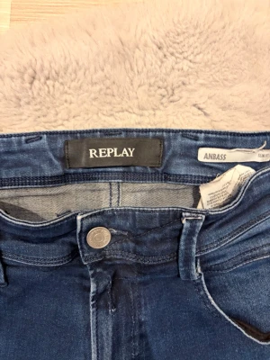 Blå slim fit jeans från Replay - Säljer ett par blå slim fit jeans från Replay, modell Anbass. Jeansen har klassisk mörkblå färg som passar det mesta. Perfekta för dig som gillar en smal passform och tidlös stil. 