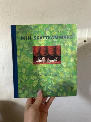 Min Skattkammare 2 - Det var en gång - Sagobok med grönt bladigt omslag och blå rygg. Boken innehåller klassiska sagor och berättelser från bland annat H.C. Andersen och Elsa Beskow. Utgiven av Natur och Kultur. Perfekt för dig som gillar nostalgi och fina illustrationer.