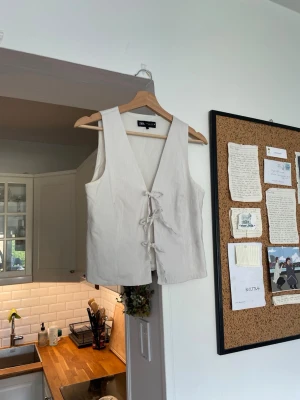 Vit väst med snörning från Zara - Stilren vit väst från Zara med djup v-ringning och snygg snörning framtill. Västen är ärmlös och har en rak passform som ger en clean look. Perfekt att styla över en skjorta eller t-shirt för en trendig layering-effekt. Passar storlek S-L