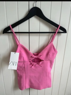 Rosa linnetopp med snörning från Zara - Supersöt rosa linnetopp från Zara med smala axelband och två dekorativa snörningar framtill. Toppen har en figurnära passform och är perfekt för dig som gillar trendiga och feminina plagg. Materialet känns mjukt och bekvämt mot huden.    (Första bilden lånad)