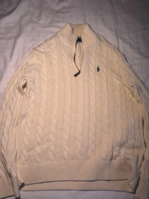 Vit stickad tröja med halvzip från Polo Ralph Lauren - Half-Zip stickad tröja från Polo Ralph Lauren. Använd 2-3 gånger bara. Så nästan som ny. Snygg och skön lite tjockare tröja man kan ha över skjortor, T-shirts osv. 