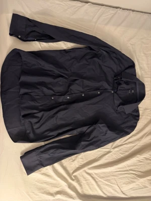 Svart skjorta från Hugo boss  - Säljer en stilren svart skjorta från Hugo Boss i storlek 43 (Regular Fit). En klassisk skjorta som passar perfekt till både fest, jobb och mer uppklädda tillfällen. Tidlös svart färg som är enkel att matcha med både kostymbyxor och jeans.