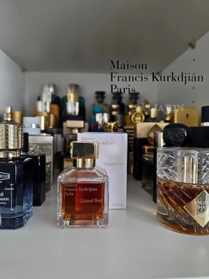 Maison Francis Kurkdjian Grand Soir 70 ml - Exklusiv parfym i elegant glasflaska med guldigt lock från Maison Francis Kurkdjian. Doften Grand Soir kommer i en fyrkantig flaska med bärnstensfärgad vätska och matchande kartong. Perfekt för dig som gillar lyxiga och sofistikerade dofter. 