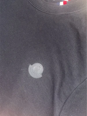 Svart sweatshirt från Moncler - Snygg svart sweatshirt från Moncler med diskret logotyp på bröstet. Tröjan har rund halsringning, långa ärmar och ribbade muddar. Perfekt för en clean och stilren look.