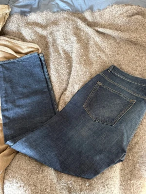 Blå raka jeans från Gant - Säljer ett par klassiska blå jeans från Gant med rak passform och fem fickor. Jeansen har normal midja, dragkedja och knapp framtill samt snygga kontrastsömmar. Perfekta till vardagslooken och tillverkade i slitstark denim.