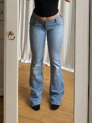 Ljusblå bootcut jeans med låg midja - Säljer ett par ljusblå bootcut jeans från ONLY med låg midja och klassiska fickor både fram och bak. Jeansen har en snygg utsvängd passform och är perfekta för dig som gillar en retro vibe. Midja: 80cm, innerben:89cm
