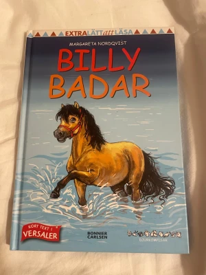 Billy Badar - Margareta Nordqvist - En färgglad barnbok med hårda pärmar, illustrerad med en söt häst som badar. Boken är skriven av Margareta Nordqvist och ingår i serien Djurkompisar. Texten är extra lätt att läsa med versaler och korta meningar. Perfekt för unga läsare som gillar djur och roliga äventyr.