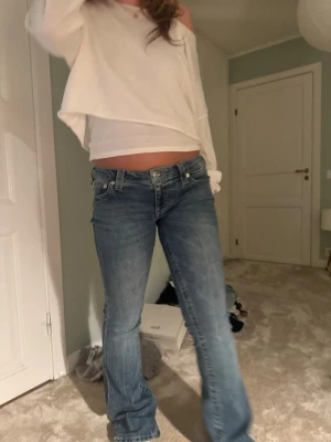 Blå bootcut jeans med låg midja - Säljer ett par klassiska blå bootcut jeans med låg midja och fem fickor. Jeansen har en lätt tvättad look och stängs med dragkedja och knapp. Perfekta för dig som gillar en avslappnad och trendig stil. Nypris 1300kr säljer för 550kr!!!!!💕💕💕