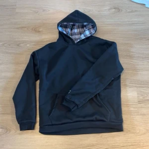 Svart hoodie med rutigt foder - Kan vändas ut och in för en helruttig look