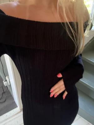 Svart ribbad offshoulder klänning - Snygg svart ribbad klänning med offshoulder-design och långa ärmar. Klänningen har en kroppsnära passform och är ifrån H&M.