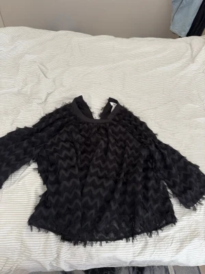 Svart blus  - Säljer en svart blus från object. Blusen har halv långa ärmar och är gjord i ett lätt, mesh-liknande material som ger en luftig känsla. Perfekt för dig som vill ha en unik och trendig look. Använd 1 gång 