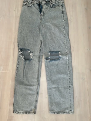  jeans med slitna knän - Säljer ett par jeans med raka ben och stora slitningar över båda knäna.