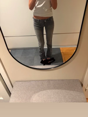 Grå raka jeans med låg midja - Säljer ett par grå jeans med rak passform och låg midja. Jeansen har klassiska fem fickor och bälteshällor. Perfekta till en avslappnad stil och passar till det mesta. Materialet ser ut att vara denim i bomull.