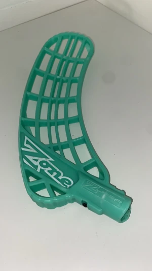 Zone innebandyblad mintgrön - Säljer ett mintgrönt innebandyblad från Zone med öppen konstruktion och tydlig logga. Bladet är tillverkat i slitstark plast och har en böjd form för bättre bollkontroll. Perfekt för dig som vill uppgradera din klubba.