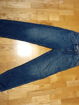 Blå raka jeans i klassisk modell - Snygga blå jeans med rak passform och fem fickor. Jeansen har en klassisk midja och subtila slitningar framtill för en avslappnad look. Tillverkade i denim, perfekt för dig som gillar tidlös stil.