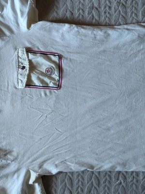 Monclet Polo - Klassisk vit pikétröja från Moncler med ikoniskt tygmärke på bröstet och fin passform.
