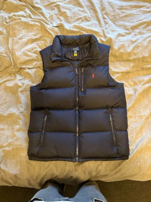Ralph Lauren puffer väst - En snygg stilren puffer väst perfekt till hösten med sin mörkblåa färg. Passar alla som bär S och håller värmen bra på sena kvällar. Bara att kontakta vid fler frågor eller bilder