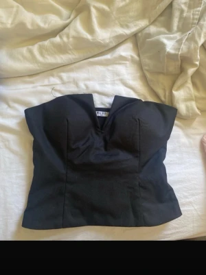 Svart korsettopp från NA-KD - Säljer en svart korsettopp från NA-KD med snygg sweetheart-urringning. Toppen är axelbandslös och har en figurnära passform som framhäver siluetten. Perfekt att styla med höga jeans eller kjol för en trendig look.