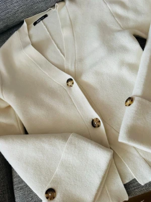 Gina Tricot vit/creme cardigan – strl S 🤍 - Jättefin stickad cardigan från Gina Tricot i storlek S. Cremevit/off-white färg med fina dekorativa knappar och snygga detaljer vid ärmarna.  Väldigt fin och elegant modell som passar perfekt till både jeans, byxor och kjol. I mycket fint skick. 🤍
