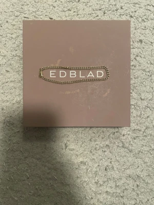Guldigt armband från Edblad - Snyggt och stilrent armband från Edblad i guldfärgad metall. Armbandet har en klassisk kedjedesign som passar perfekt till alla outfits. Lätt att bära och kombinera med andra smycken för en personlig stil.
