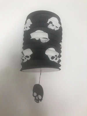Halloweenlyktor med dödskallar & fladdermöss - Två papperslyktor för halloween, en svart med vita dödskallar och en lila med svarta fladdermöss. Båda har matchande dekorationer hängande i botten. Perfekta som dekoration till maskerad eller cosplay. 145kr/st 