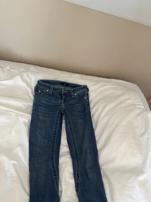 Blå low rise flare jeans Joey - Säljer ett par blå jeans med low rise och flare-modell från Joey. Klassisk femficksdesign, dragkedja och knapp framtill. Jeansen har en snygg tvättad look och är tillverkade i denim. Perfekta för dig som gillar retrovibbar och vill ha ett par bekväma jeans med utsvängda ben. Dem har dock gått sönder lite(kolla på bilderna) vid frågor och funderingar är det bara att skriva❤️