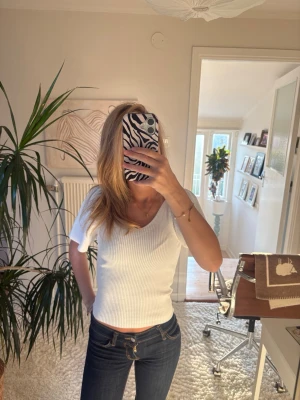Vit ribbad topp med puffärm och knyt - Supersnygg vit ribbad topp med puffärmar och v-ringning. Toppen har ett fint knyt i ryggen. Perfekt att styla med jeans eller kjol för en trendig look. Storlek xs från only!!🤍