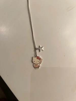 Hello Kitty halsband med stjärnhänge - Sött halsband med en silverfärgad kedja och två hängen