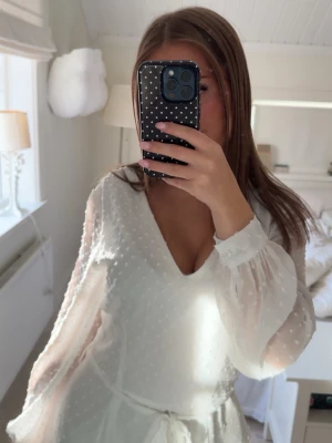Vit volangklänning - Superfin vit klänning från märket Sisters point🤍med v-ringning, transparenta långärmar och volangdetaljer. Klänningen har ett knyt i midjan och ett diskret prickigt mönster i tyget. Perfekt för sommarens alla tillfällen. Endast använd 2 gånger! Så ett fint skick💗Storlek M men passar mig som S💗