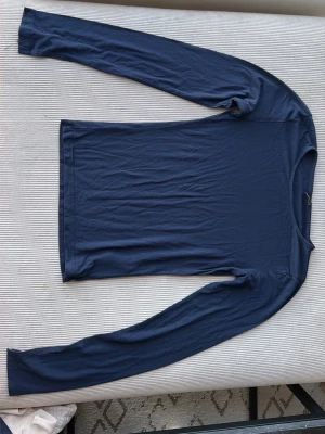 Mörkblå långärmad topp Gina Tricot - En enkel och stilren mörkblå långärmad topp från Gina Tricot. Toppen har en rund halsringning och är gjord i ett mjukt, stretchigt material som sitter skönt mot kroppen. Perfekt att matcha med jeans eller kjol.