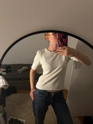 Vit ribbad topp med puffärm - Säljer en vit ribbad topp med korta puffärmar och rund hals. Toppen har en slim passform och är tillverkad i ett stretchigt material som sitter snyggt på kroppen. Perfekt att styla med jeans eller kjol för en clean look. Är st xxs men sitter mer som xs/s