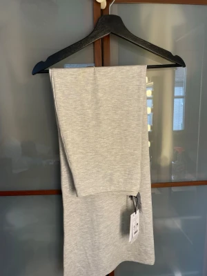 Ljusgrå långkjol i mjukt material - Säljer en enkel och stilren ljusgrå långkjol i mjukt och stretchigt material. Kjolen har en rak passform och är perfekt för dig som gillar minimalistisk stil. Färgen är melerad grå och tyget känns riktigt skönt mot huden.