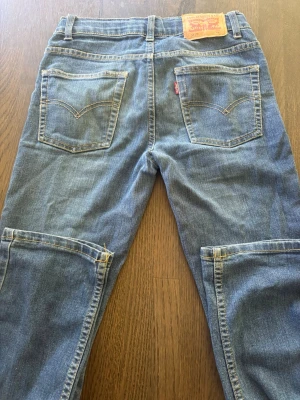 Levi's 511 Slim blå jeans - Säljer ett par klassiska blå Levi's 511 Slim jeans i denim med raka ben och snygga bakfickor. Jeansen har gul kontrastsöm och den ikoniska Levi's-lappen bak i midjan. Perfekta för dig som gillar en smalare passform och tidlös stil.