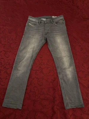 Grå regular fit diesel jeans med slitningar - Snygga grå regular fit Diesel jeans med diskreta slitningar och klassisk femficksmodell. Jeansen har en något tvättad look och raka ben. Passar perfekt till en avslappnad stil och är lätta att matcha med olika plagg. Priset går alltid att diskutera. Var inte blygs för att kontakta!😁