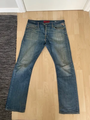 Replay jeans waiton - Säljer ett par klassiska blå jeans med raka ben och snygga slitningar på knäna. Jeansen har fem fickor, gylf med knapp och dragkedja samt ljusa tvättade partier för en cool look. Perfekta till vardagsstilen! Modell weitom, kolla på alla bilder nogrant och notera lagningen på knäna❗️❗️❗️
