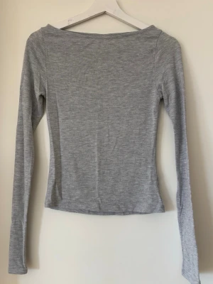 Intimissimi dupe från Nelly - En enkel och stilren ljusgrå långärmad topp med rund halsringning. Tillverkad i ett mjukt och stretchigt material som sitter skönt mot kroppen. Perfekt att matcha med jeans eller kjol för en clean look.