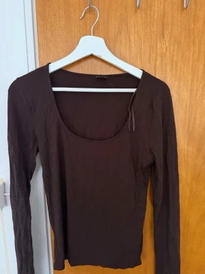 Två långärmade toppar i brunt och beige - Säljer två basic långärmade toppar med rundad urringning, en i mörkbrunt och en i beige från Gina tricot. Perfekta att styla lager på lager eller bära som de är. Tillverkade i mjuk bomull för en skön känsla och normal passform. Skrynkliga på bilderna då de legat nervikta i en låda.