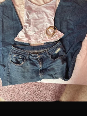 Blå baggy jeans med raka ben - Säljer ett par blå baggy jeans med raka ben och låg midja. Jeansen har klassiska fem fickor, bälteshällor och slitningar vid ena fickan fram. Materialet är denim i bomull och passformen är avslappnad och loose fit.