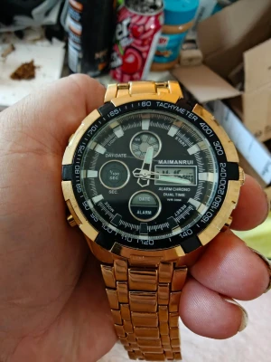 Guldig klocka från Maimanrui - Stilren klocka från Maimanrui med guldig länk och svart urtavla. Klockan har digitala och analoga funktioner, tachymeter, alarm och datumvisning. Perfekt accessoar för dig som gillar detaljer och snygg design.