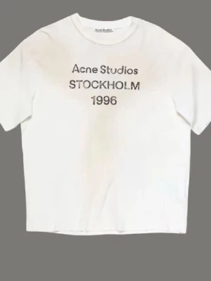 Vit t-shirt Acne Studios Stockholm - Vit t-shirt från Acne Studios med tryck 'Acne Studios STOCKHOLM 1996' på bröstet. Klassisk rund hals och korta ärmar. Perfekt basic med stilren design och skön passform.