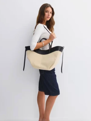 Beige och svart väska från Gina tricot  - Stilren shoppingväska i beige canvas med svarta detaljer och handtag i konstläder. Väskan har en rymlig form och långa axelband som gör den enkel att bära. Perfekt för dig som vill ha plats för allt du behöver under dagen. Helt ny med prislapp 