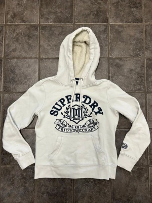 Superdry hoodie med fodrad luva - Snygg vit dam hoodie från Superdry. Mycket bra skick. Tröjan är i storlek 36 som motsvarar xs/s. Pris kan diskuteras!